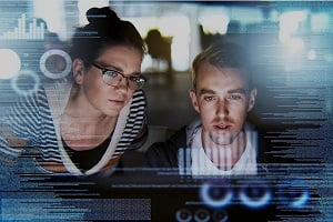 Two people looking on a computer screen with a code