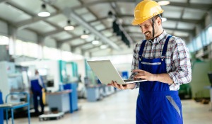 Ein Mann mit einem Laptop in einer Fabrik